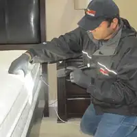 Bed bug inspection technician checking a mattress and bed frame for signs of infestation in Fort Wayne, IN