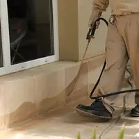 General pest control technician spraying exterior perimeter around a home in Fort Wayne, IN